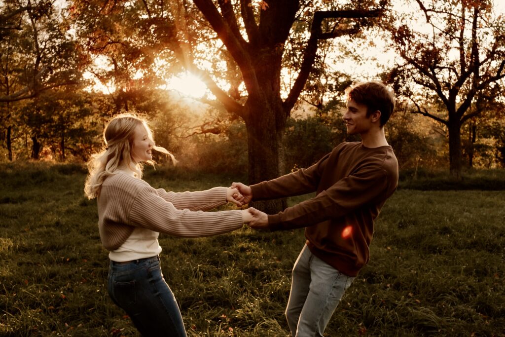 Verliebtes Paar tanzt händchenhaltend bei Sonnenuntergang im Park bei Bad Muskau – natürliche Emotionen