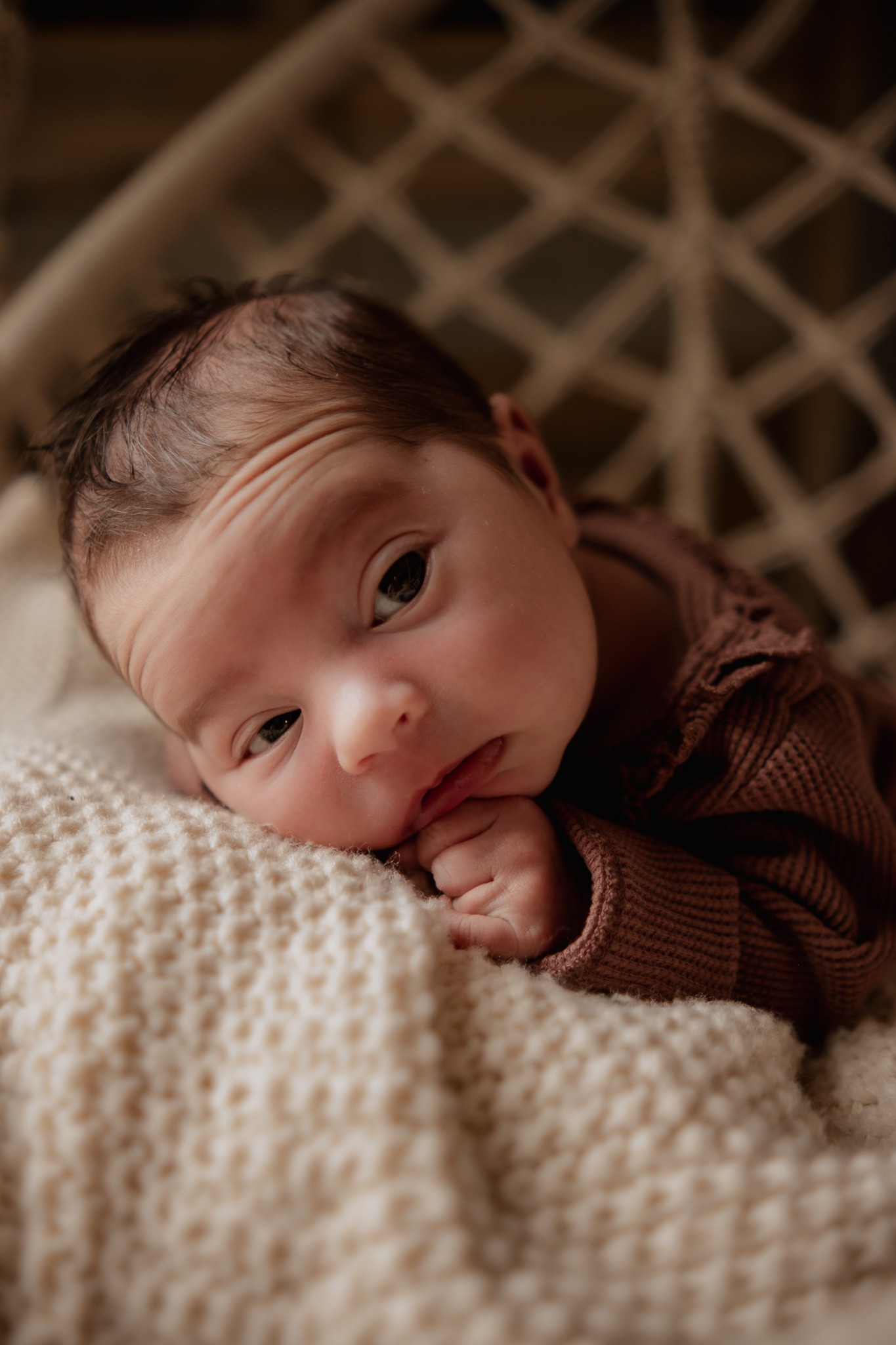 Neugeborenes Baby schläft friedlich im Körbchen – natürliche Neugeborenenfotografie in liebevollem Bohostil